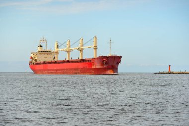 Europoort 'tan denize açılan bir vinçle büyük kırmızı bir yük gemisi (kargo gemisi). Açık mavi gökyüzü ve sirrus bulutları. Rotterdam, Hollanda. Küresel iletişim, lojistik, endüstri teması