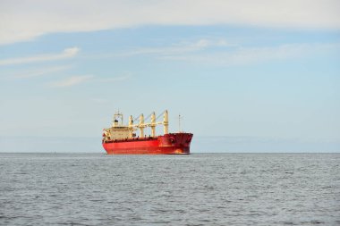 Europoort 'tan denize açılan bir vinçle büyük kırmızı bir yük gemisi (kargo gemisi). Açık mavi gökyüzü ve sirrus bulutları. Rotterdam, Hollanda. Küresel iletişim, lojistik, endüstri teması