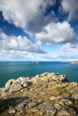 Pointe de Pen-Hir 'in kayalık sahili, uçurumlara yakın. Bulutlu mavi gökyüzü, masmavi su, fırtınalı dalgalar. Dramatik bulut manzarası. Crozon Yarımadası, Britanya, Fransa