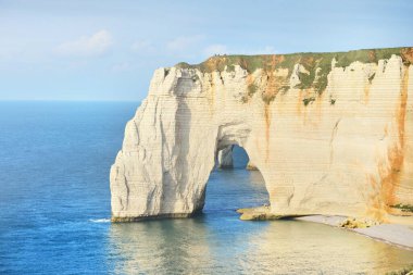 Gün batımında Etretat beyaz uçurumlarının manzaralı panoramik görüntüsü. Dramatik gökyüzü, gök mavisi su. Fransa, Normandiya 'da yaz tatili. Seyahat yerleri, ulusal dönüm noktaları, geziler, tarih.