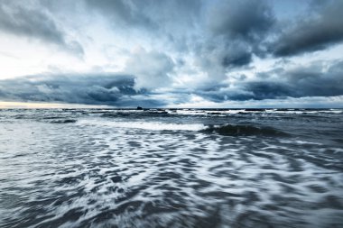 Kışın Baltık Denizi 'nin üzerindeki fırtına bulutları, uzun pozlama. Dramatik günbatımı gökyüzü, dalgalar ve su sıçramaları. Koyu deniz manzarası. Almanya