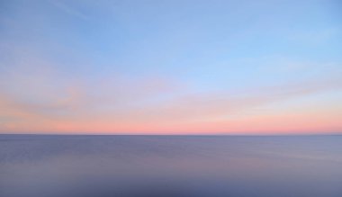 Renkli günbatımı gökyüzünün altında Baltık Denizi. Göz kamaştırıcı deniz manzarası. Pembe bulutların arasından geçen altın gün batımı ışığı. Uzun pozlama. Huzur sahnesi. Riga Körfezi, Letonya