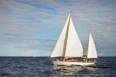 Eski, pahalı, ahşap bir yelkenli (yawl) yakın çekim, açık denizde yelken. Şaşırtıcı bulut manzarası. Maine sahili, ABD