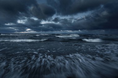 Kışın Baltık Denizi 'nin üzerindeki fırtına bulutları, uzun pozlama. Dramatik günbatımı gökyüzü, dalgalar ve su sıçramaları. Koyu deniz manzarası. Almanya