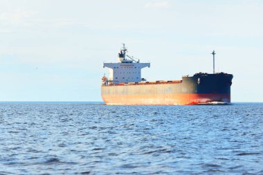 Büyük bir yük gemisi (kargo gemisi) Europoort 'tan açık denizlere açılır. Açık mavi gökyüzü ve sirrus bulutları. Rotterdam, Hollanda. Küresel iletişim, lojistik, endüstri teması