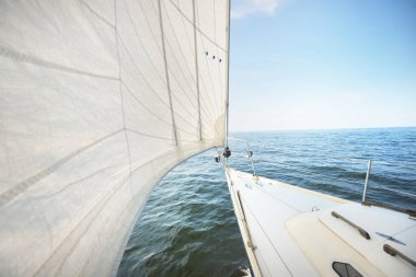 Güneşli bir yaz gününde beyaz bir yat denize açılıyor. Güverteden pruva ve yelkenlere kadar yukarıdan aşağıya doğru. Dalgalar ve su sıçramaları. Açık mavi gökyüzü. Baltık Denizi, İsveç