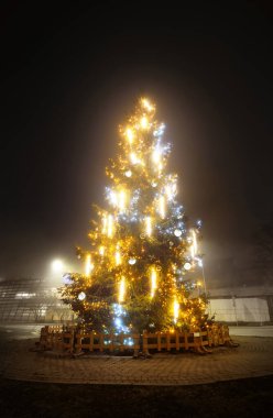 Geceleyin sisli bir sokakta güzel kristal mücevherlerle aydınlatılmış Noel ağacı. Riga, Letonya. Görüntü, gelenek, kutlama, dekorasyon, kış tatilleri, grafik kaynaklar
