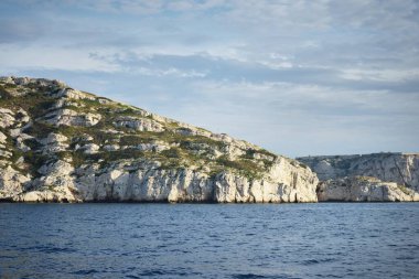 Kayalık kıyılar (uçurumlar) yakın çekim, yelkenli teknenin manzarası. Frioul takımadaları, Akdeniz, Marsilya Körfezi, Fransa. Seyahat yerleri, ulusal dönüm noktaları, geziler, tatiller.