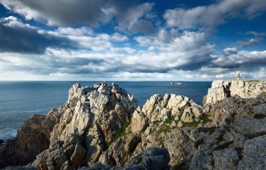Pointe de Pen-Hir 'in kayalık sahili, uçurumlara yakın. Bulutlu mavi gökyüzü, masmavi su, fırtınalı dalgalar. Dramatik bulut manzarası. Crozon Yarımadası, Britanya, Fransa