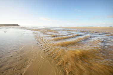 Douarnenez körfezinin kumlu sahilinden bir manzara. Açık mavi gökyüzü. Sudaki yansımalar. Dalgalar ve su sıçramaları. Brittany, Fransa. Seyahat yerleri, boş zaman etkinlik teması