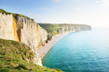 Gün batımında Etretat beyaz uçurumlarının manzaralı panoramik görüntüsü. Dramatik gökyüzü, gök mavisi su. Fransa, Normandiya 'da yaz tatili. Seyahat yerleri, ulusal dönüm noktaları, geziler, tarih.