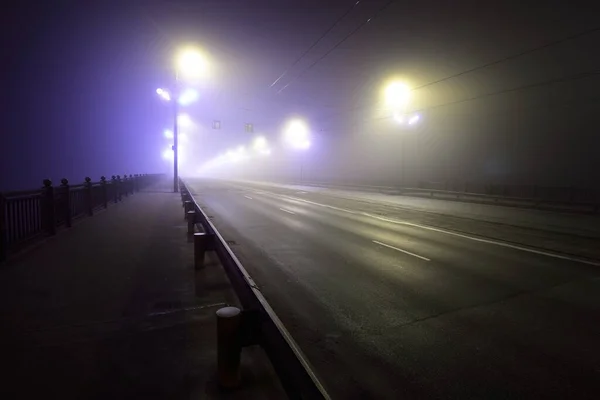 在浓雾中 人行横道和公路穿过灯火辉煌的空石桥 灯笼特写 多加瓦河 拉脱维亚 概念图像 霓虹灯色 — 图库照片