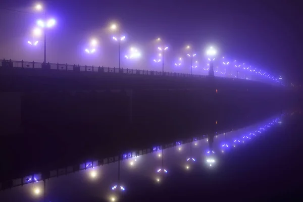 夜雾中照亮了空旷的石桥 灯笼特写 对称反射在水面上 天然的镜子 多加瓦河 拉脱维亚 概念图像 霓虹灯色 — 图库照片