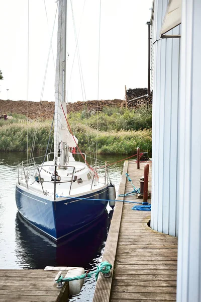 青いスループは 小さな村で クローズアップ木製の桟橋に係留ヨットを操縦した 背景には薪 ノルウェー — ストック写真