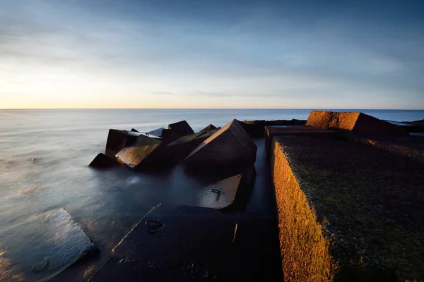 在五彩缤纷的夕阳天下的防波堤 令人惊叹的海景 金色的夕阳透过蓝色的云彩 长期暴露 波罗的海 里加湾 拉脱维亚 — 图库照片