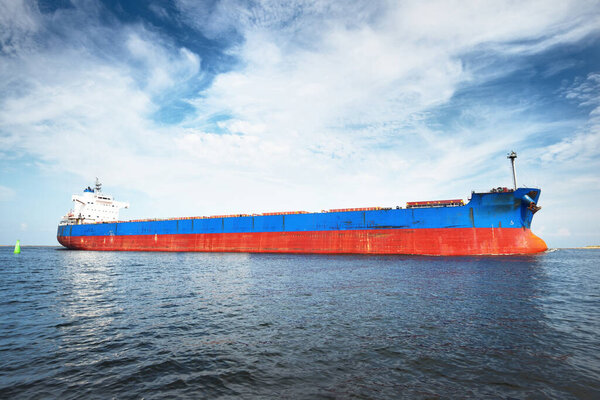 Large blue bulk carrier (ship) sailing in the Baltic sea to Riga port, Latvia. A view from the yacht. General cargo. Global communications, logistics, industry, freight transportation