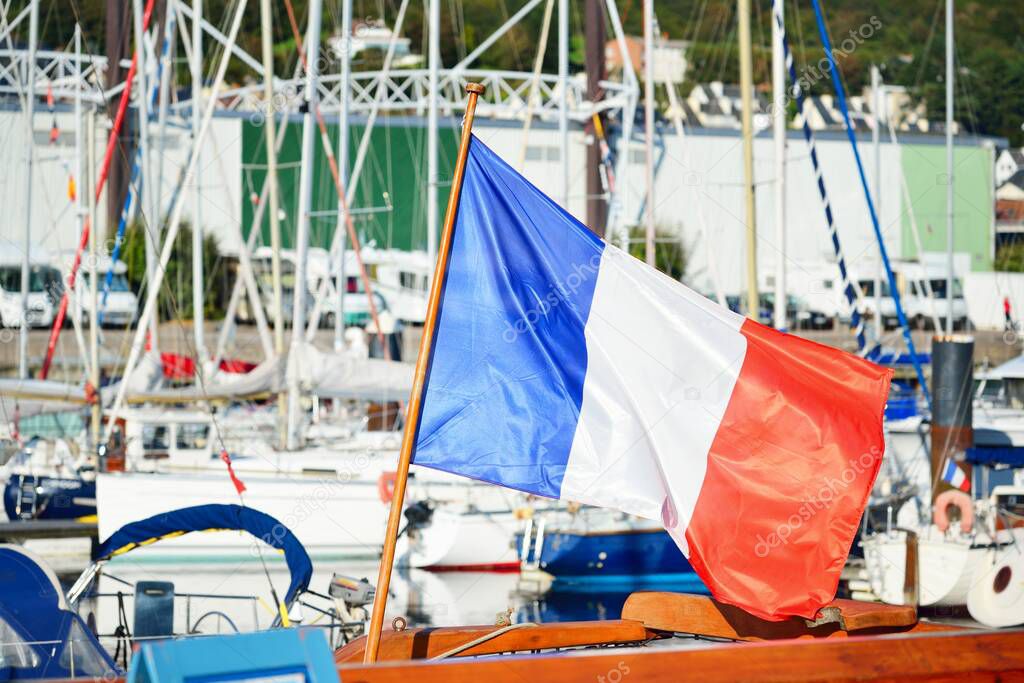 Elegant fishing boat anchored in a yacht marina on a clear day. Fcamp, Normandy. Flag of France close-up. Transportation, sport, recreation, national landmark, sightseeing, travel destinations.