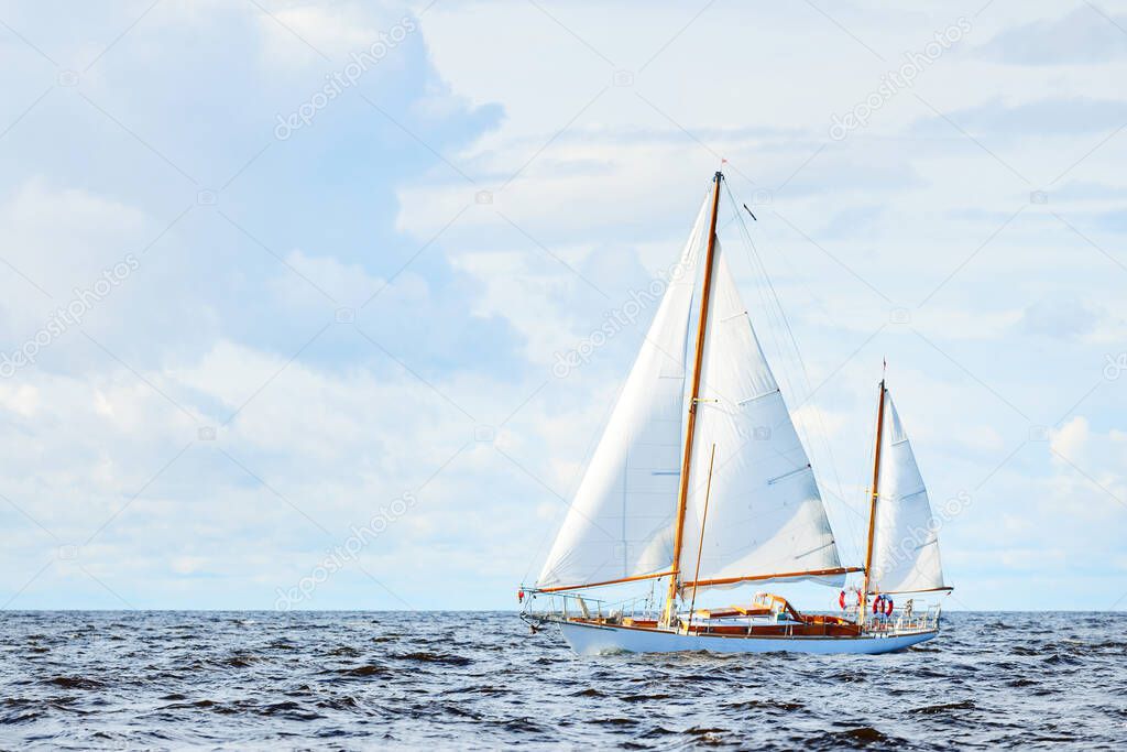 Old expensive vintage wooden sailboat (yawl) close-up, sailing in an open sea. Dramatic cloudscape. Coast of Maine, US