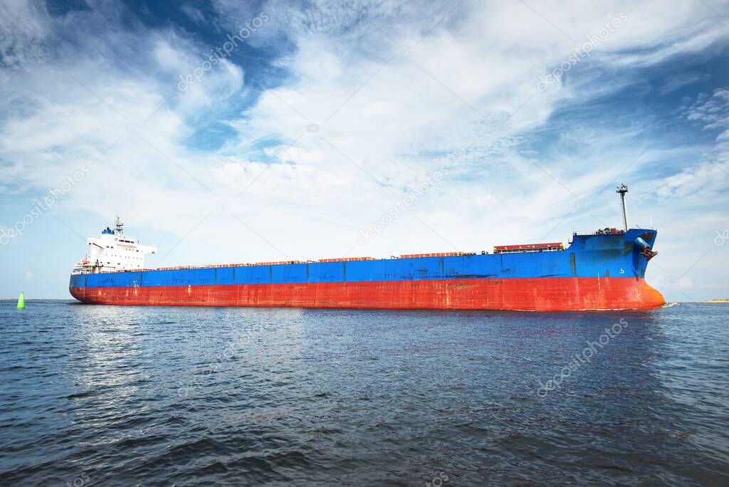 Large blue bulk carrier (ship) sailing in the Baltic sea to Riga port, Latvia. A view from the yacht. General cargo. Global communications, logistics, industry, freight transportation