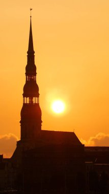 Riga, Letonya 'daki Aziz Peter Kilisesi' nin silueti. Gün doğumunda. Parlak gökyüzü, altın güneş ışığı. Manzaralar, simgeler, kültür ve din, seyahat yerleri