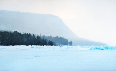 Kandalaksha körfezinin buz basıncıyla kaplı sırtı fırtınalı bir gökyüzünün altında. Renkli akşam bulutları. Arka planda Kola Yarımadası 'nın dağları ve kozalaklı ormanları var. Beyaz deniz, Kutup dairesi, Karelia, Rusya