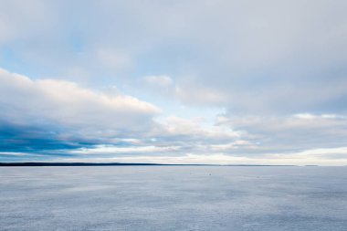 Kış manzarası. Gün batımında donmuş karla kaplı göl manzarası. Arka planda orman var. Renkli akşam bulutları. Onega Gölü, Karelia, Rusya