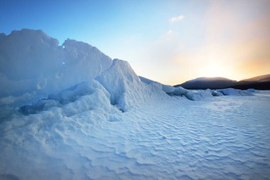 Gün batımında Kandalaksha Körfezi 'nin buz basıncı sırtı. Renkli akşam bulutları. Arka planda Kola Yarımadası 'nın dağları ve kozalaklı ormanları var. Beyaz deniz, Kutup dairesi, Karelia, Rusya