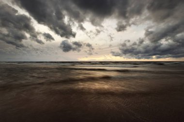 Göz kamaştırıcı gün batımı gökyüzü, Baltık Denizi, Danimarka. Fırtına dalgaları, renkli bulutların arasından geçen altın akşam güneşi. Uzun pozlama