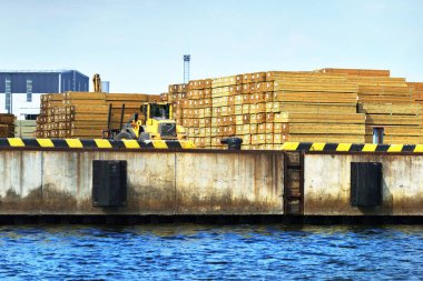 Sarı forklift ahşap bir kargoyla yakından çalışıyor. Riga Limanı, Baltık Denizi, Letonya