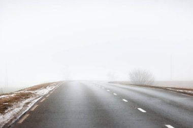 Yoğun beyaz bir sabah sisinde kırsal tarlalarda keskin bir dönüş yapan boş bir otoyol. Yerde taze kar var. Yalnızlık, özgürlük, tehlikeli sürüş kavramları. Polonya 'da bahar