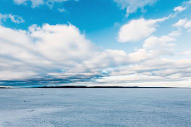 Kış manzarası. Gün batımında donmuş karla kaplı göl manzarası. Arka planda orman var. Renkli akşam bulutları. Onega Gölü, Karelia, Rusya
