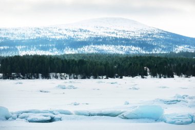 Kandalaksha körfezinin buz basıncıyla kaplı sırtı fırtınalı bir gökyüzünün altında. Renkli akşam bulutları. Arka planda Kola Yarımadası 'nın dağları ve kozalaklı ormanları var. Beyaz deniz, Kutup dairesi, Karelia, Rusya