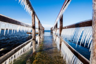 Güneşli bir günde, karla kaplı eski, paslı iskele. Buz parçaları yakın plan. Baltık Denizi, Letonya