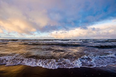 Renkli kış günbatımı. Kuzey denizi üzerinde soğuk fırtınalı dalgalar ve bulutlar, Hollanda