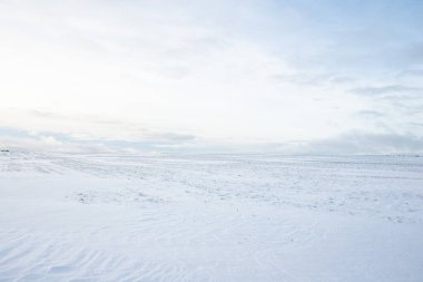 Gün batımında karla kaplı kırsal alanın panoramik manzarası. Akşam bulutları. Norveç