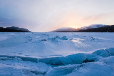 Gün batımında Kandalaksha Körfezi 'nin buz basıncı sırtı. Renkli akşam bulutları. Arka planda Kola Yarımadası 'nın dağları ve kozalaklı ormanları var. Beyaz deniz, Kutup dairesi, Karelia, Rusya