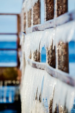 Güneşli bir günde, karla kaplı eski, paslı iskele. Buz parçaları yakın plan. Baltık Denizi, Letonya
