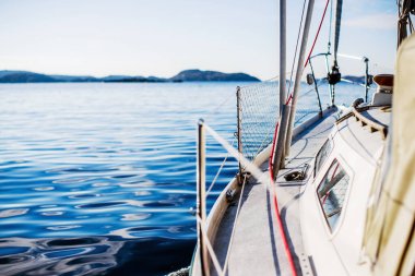 Güneşli bir günde beyaz bir yat denize açılıyor. Güverteden pruvaya, direğe ve yelkenlere bir manzara. Norveç