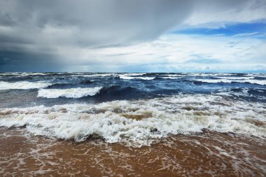 Baltık Denizi 'nin üzerindeki koyu mavi bulutlu gökyüzü, fırtına dalgaları. Deniz kıyısından bir manzara. Letonya