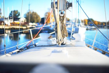 Açık bir günde yat limanındaki bir rıhtıma demirlemiş beyaz yelkenli. Güverteden pruvaya, direğe ve teçhizata kadar yakın çekim. Tatiller, spor, amatör eğlence yelkenciliği, gemi yolculuğu.