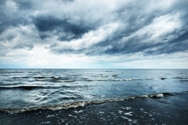Baharda Baltık Denizi 'nin kumlu kıyılarında fırtına bulutları, dramatik gökyüzü, dalgalar ve su sıçramaları. Koyu deniz manzarası. - Letonya. Hava, iklim değişikliği, ekoloji, çevre, doğa