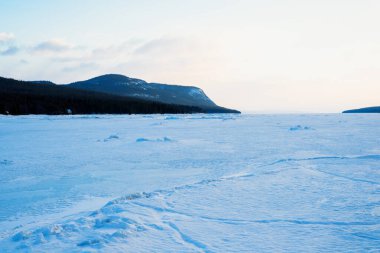 Gün batımında Kandalaksha Körfezi 'nin buz basıncı sırtı. Renkli akşam bulutları. Arka planda Kola Yarımadası 'nın dağları ve kozalaklı ormanları var. Beyaz deniz, Kutup dairesi, Karelia, Rusya