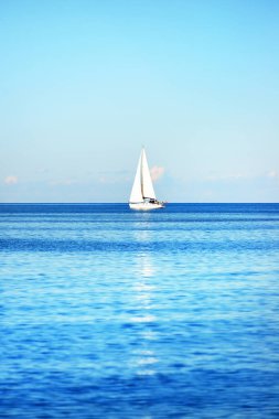 Açık ve güneşli bir günde Akdeniz 'de yelkenli dolu bir yat, İspanya. Beyaz bulutlu mavi gökyüzü, suda yansımalar.