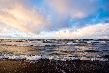Renkli kış günbatımı. Soğuk fırtınalı dalgalar ve bulutlar Baltık Denizi üzerinde, Letonya