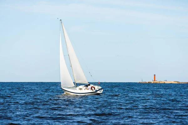ホワイトスループは晴れた日にヨットを操縦しました 背景に灯台 曇った青空 リガ湾 バルト海 ラトビア — ストック写真