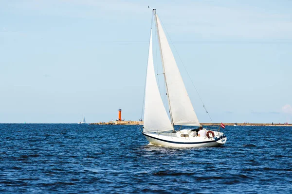 ホワイトスループは晴れた日にヨットを操縦しました 背景に灯台 リガ湾 バルト海 ラトビア — ストック写真