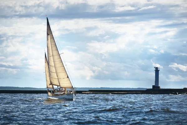 曇りの日にヴィンテージの白い木製のセーリングボート帆 背景の灯台 — ストック写真