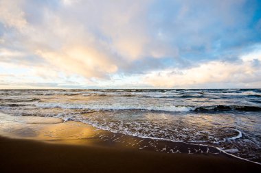 Renkli kış günbatımı. Soğuk fırtınalı dalgalar ve bulutlar Baltık Denizi üzerinde, Letonya