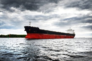 Büyük siyah kargo gemisi, yakın plan. Karanlık fırtına gökyüzü. Arka planda Riga Limanı. Baltık Denizi, Letonya