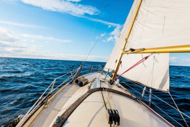 Açık bir günde yelkenli dolu bir yat. Güverteden pruvaya ve yelkenlere bir manzara. Dalgalar ve su sıçramaları. Baltık Denizi, Letonya